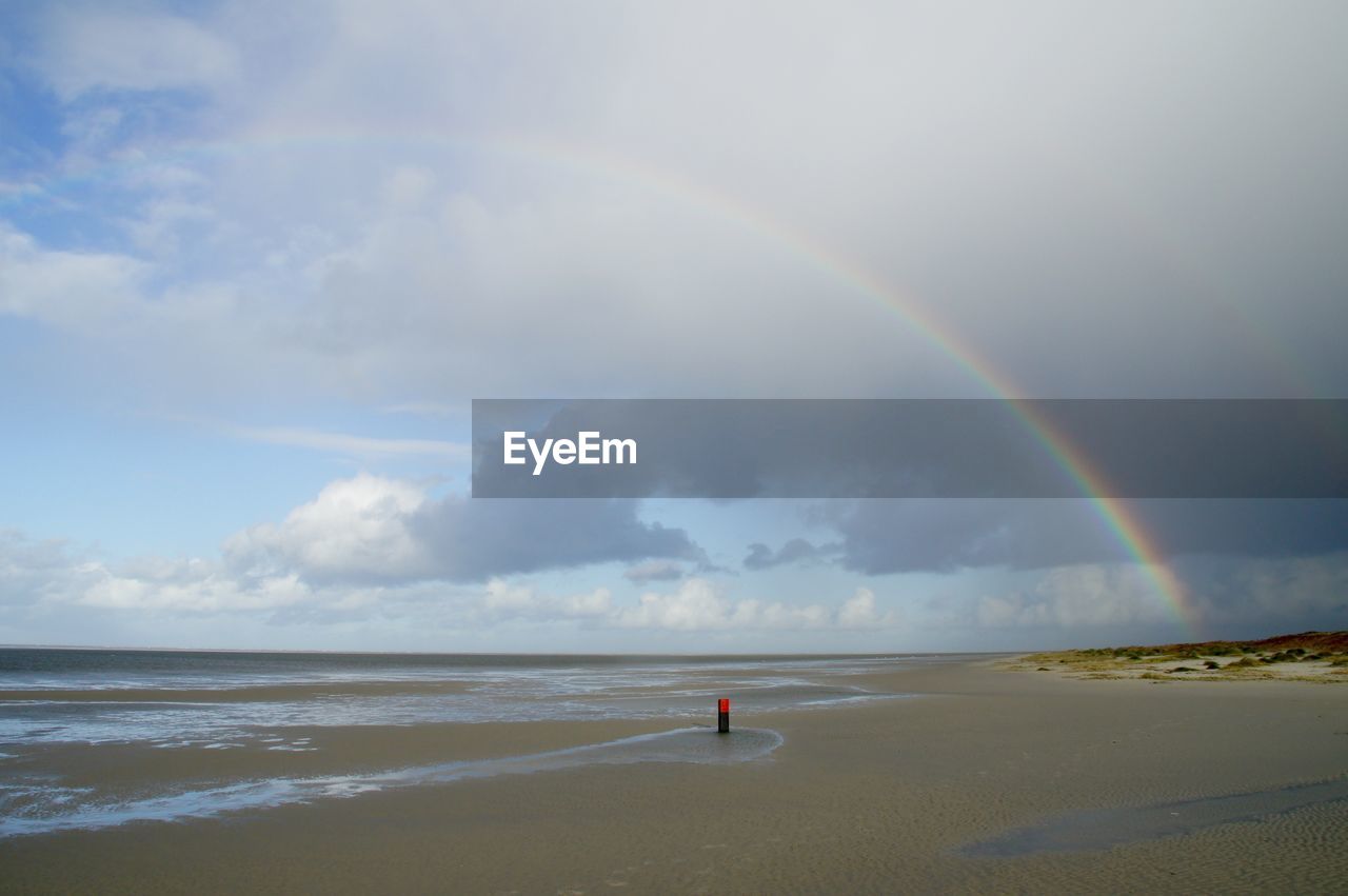 Scenic view of rainbow over sea against sky