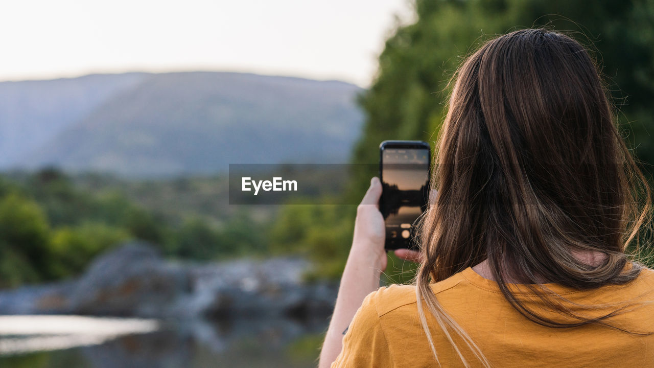 Rear view of woman photographing outdoors