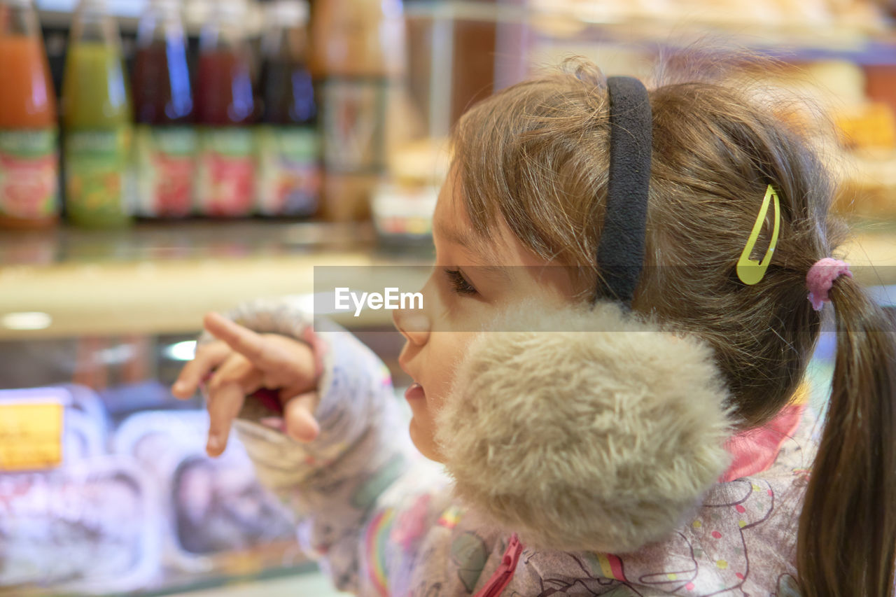 Cute girl wearing ear muffs standing at store