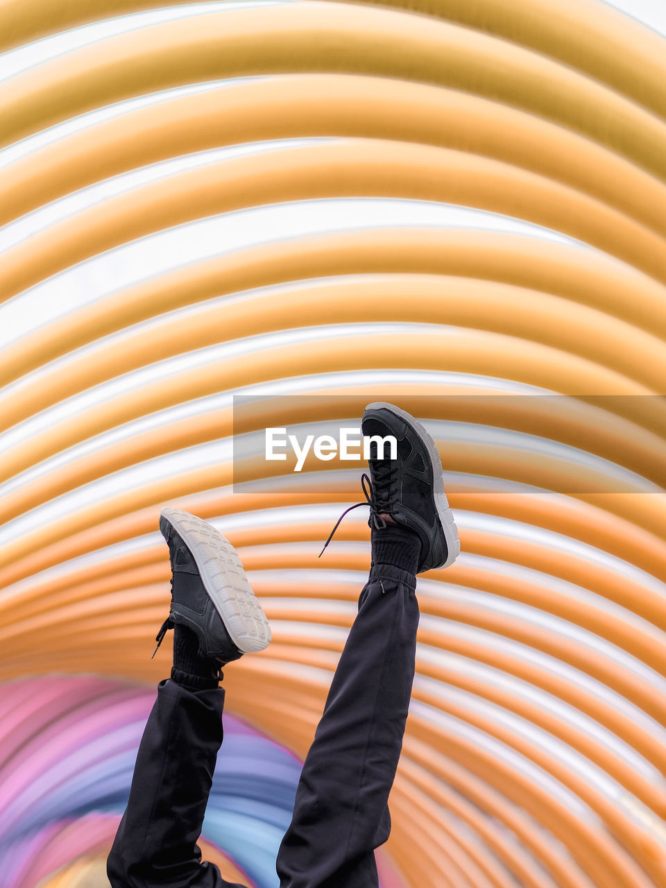 Low section of man's feets up in the air against colorful curves background