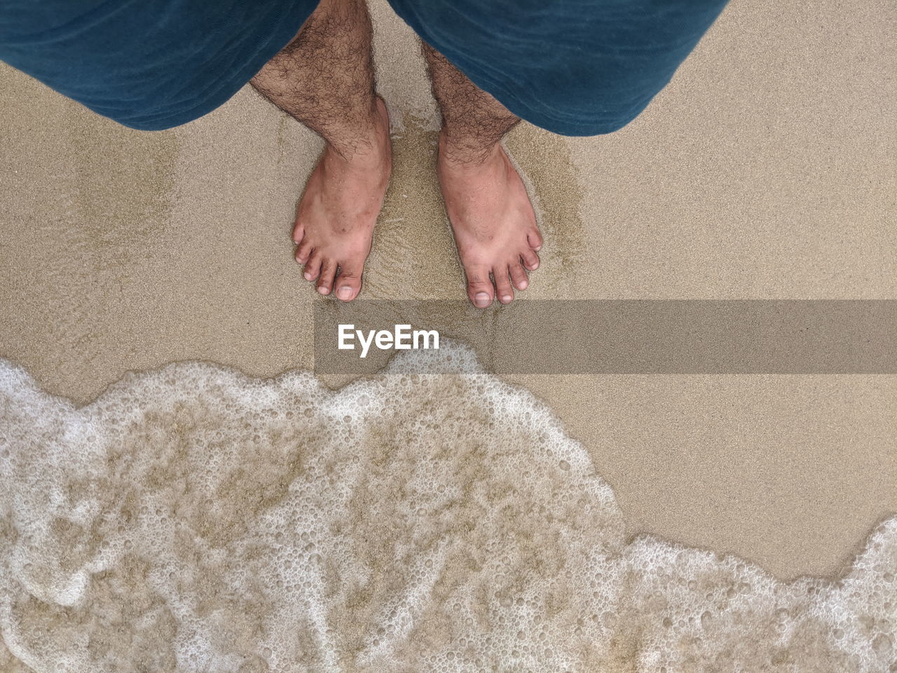 Low section of man standing at shore