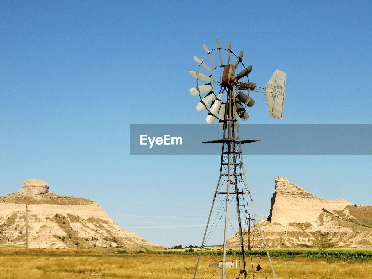 American-style windmill on field against clear blue sky