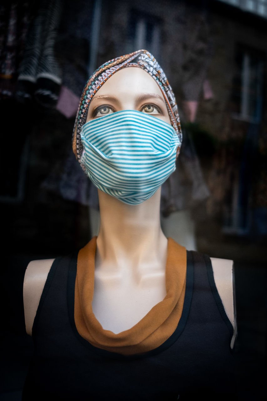 PORTRAIT OF A SERIOUS YOUNG WOMAN WEARING MASK