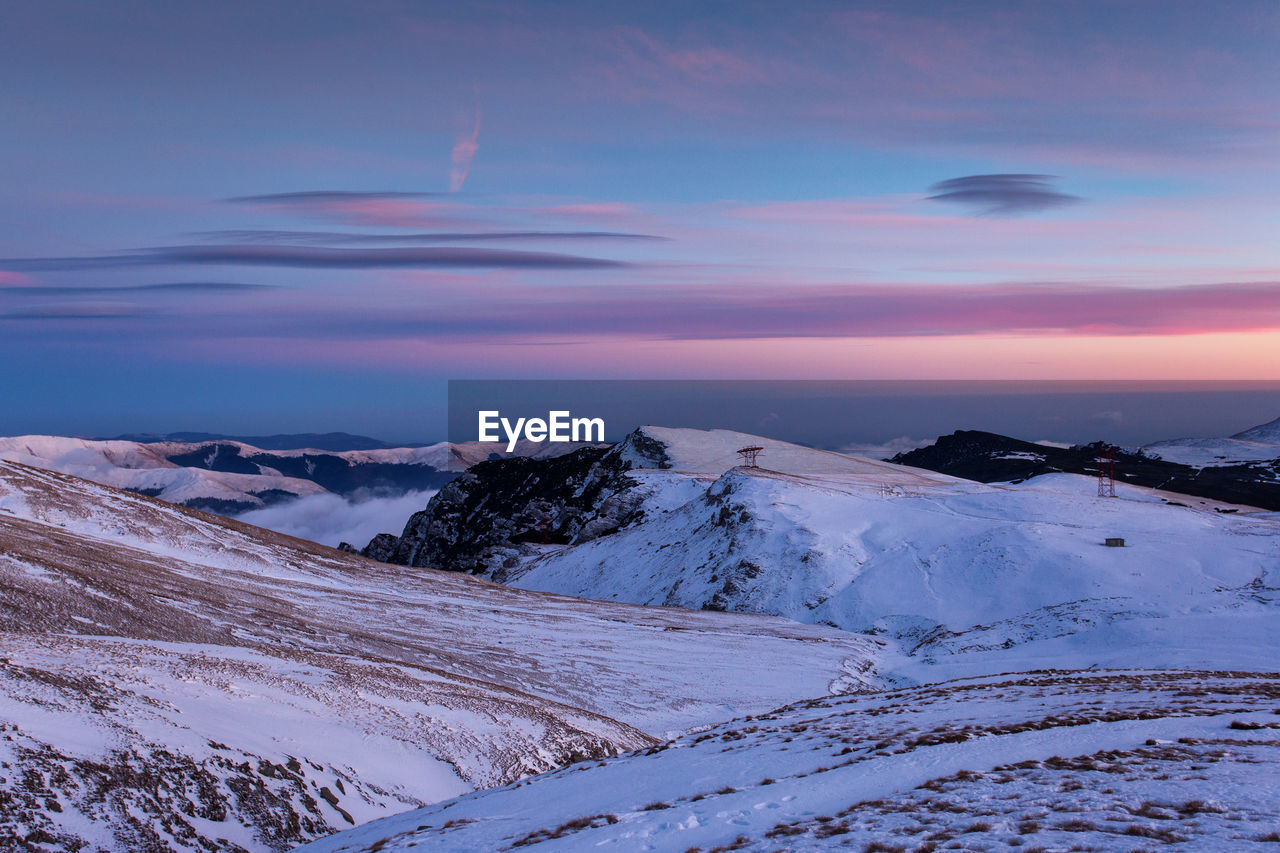 Scenic view of snow covered mountains against sky during sunset