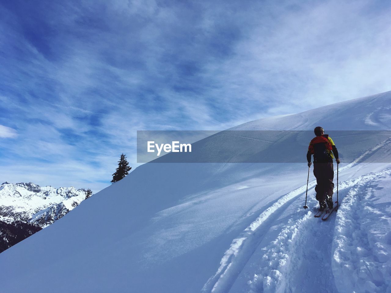 Rear view of man skiing on snowcapped mountain against sky