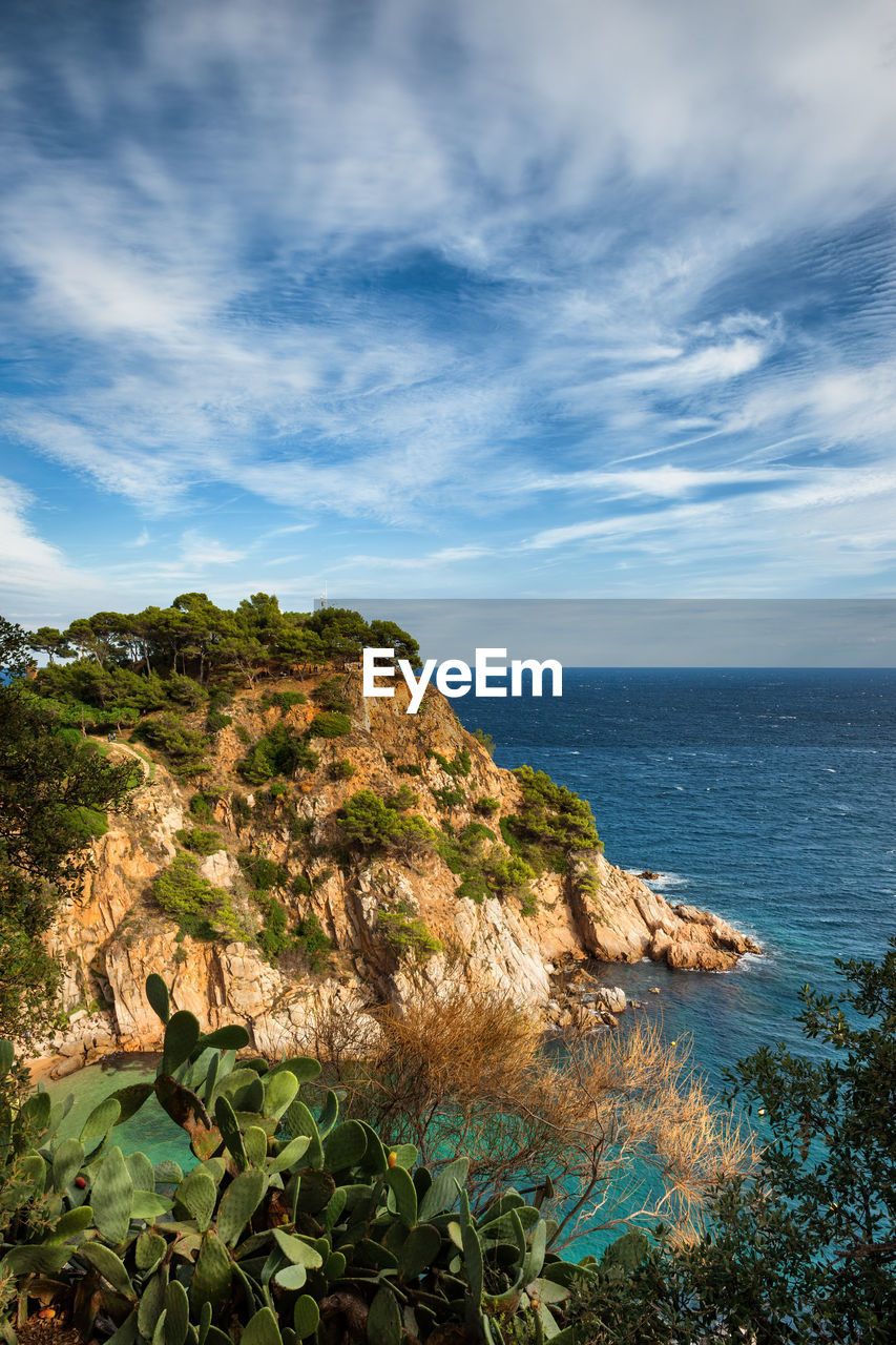 SCENIC VIEW OF ROCKY BEACH AGAINST SKY