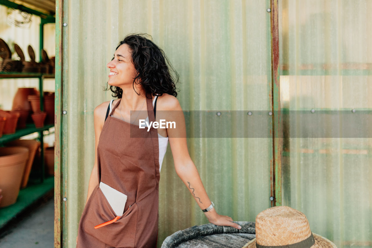 Young female potter entrepreneur looking away while standing in pottery shop