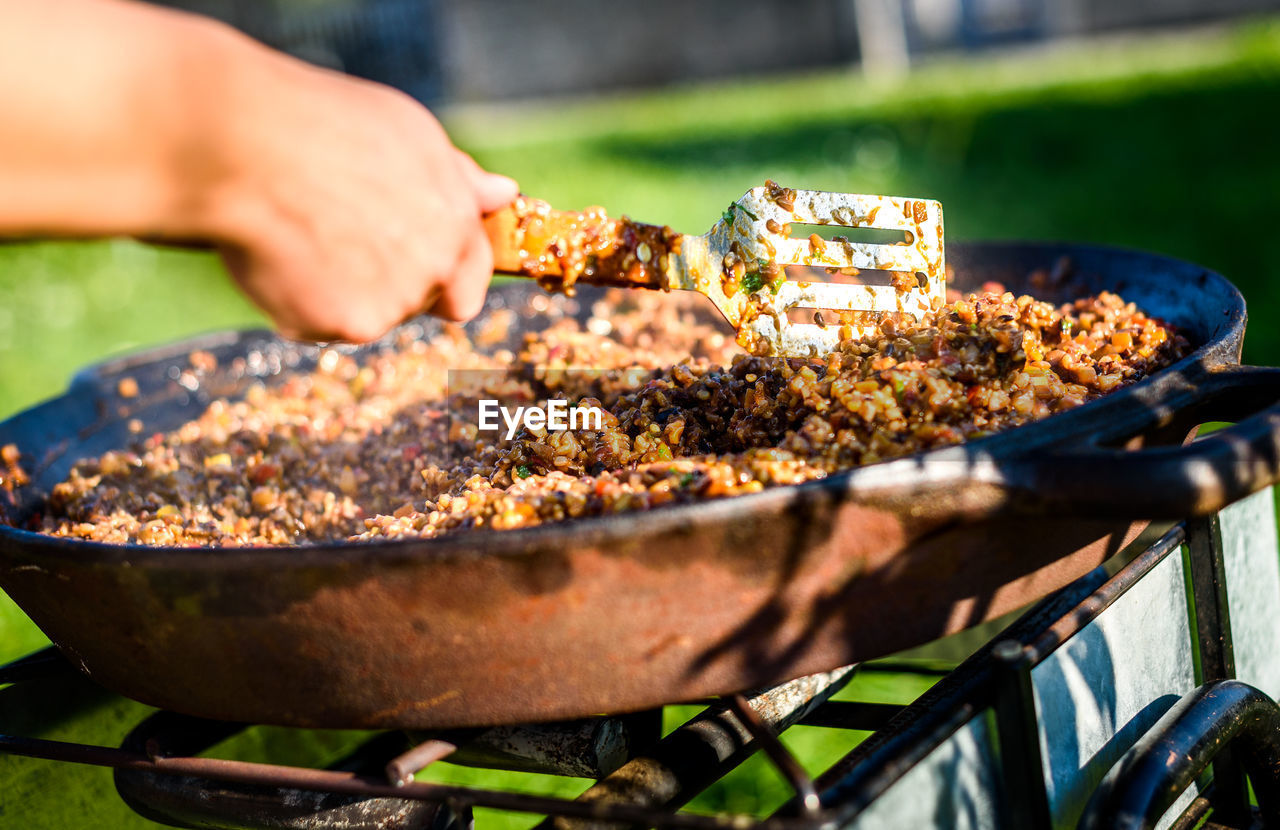 Close-up of man preparing food on barbecue grill in yard