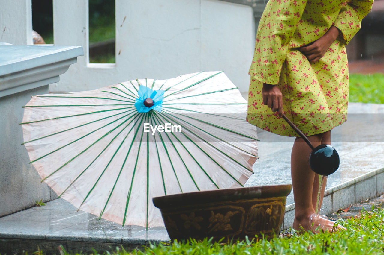 Low section of woman washing feet using bamboo dipper