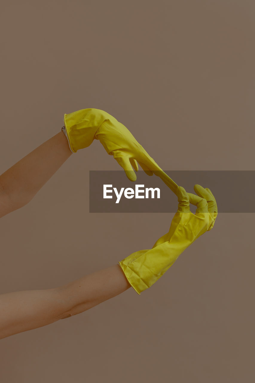 Woman taking off a pair of yellow rubber gloves