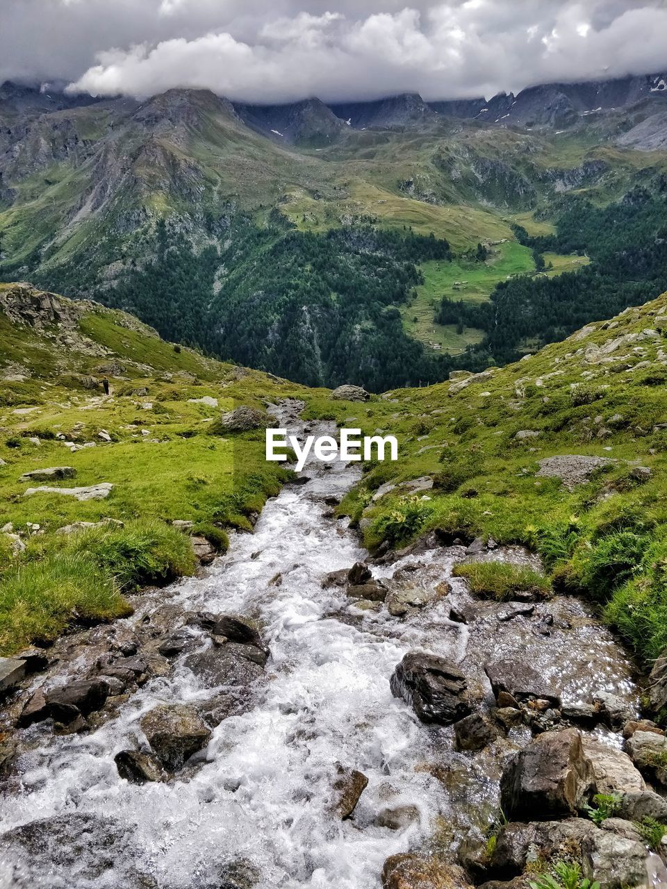 Scenic view of stream by mountains against sky