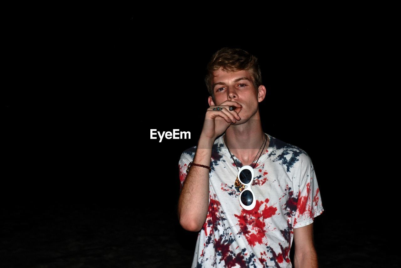 Man smoking cigar against black background