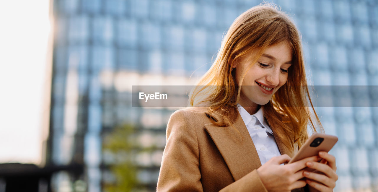 Professional businesswoman smiling and using mobile phone in formal attire