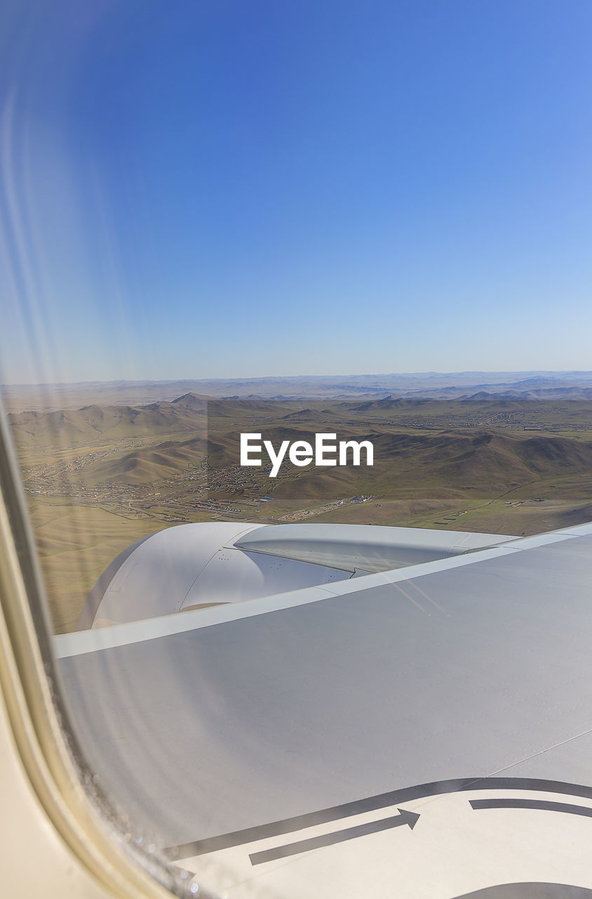 Low angle view of airplane wing over landscape