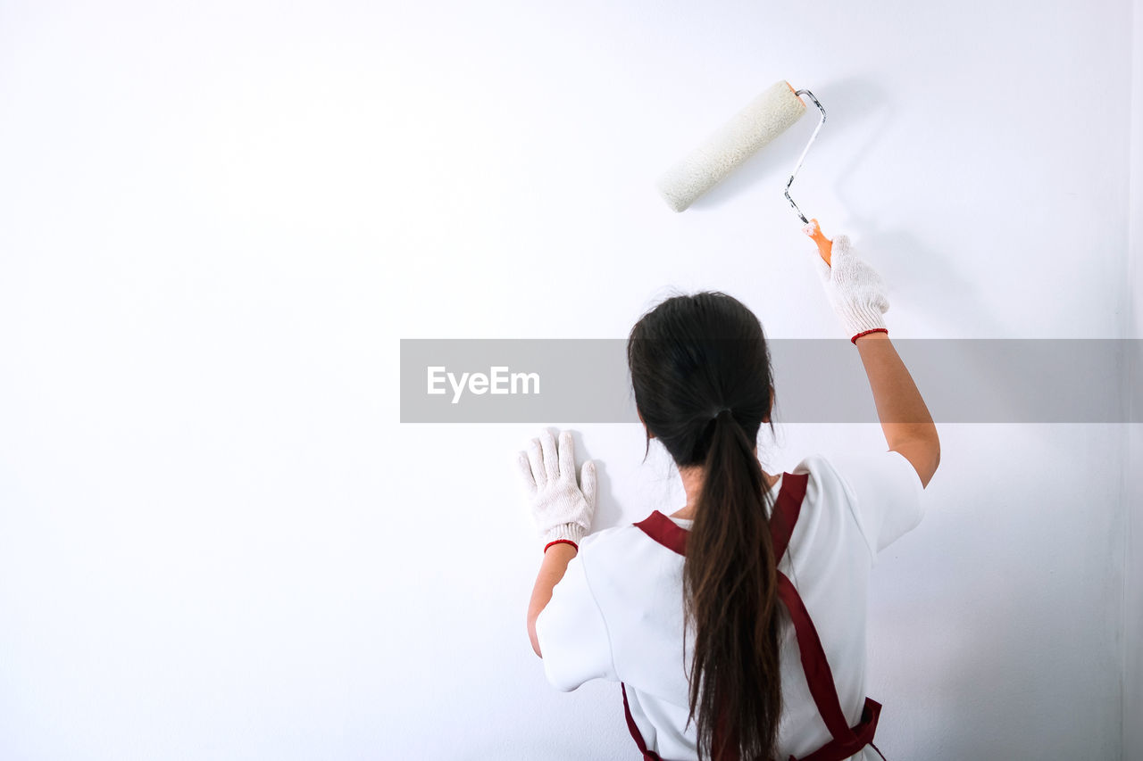 Rear view of woman painting wall at home