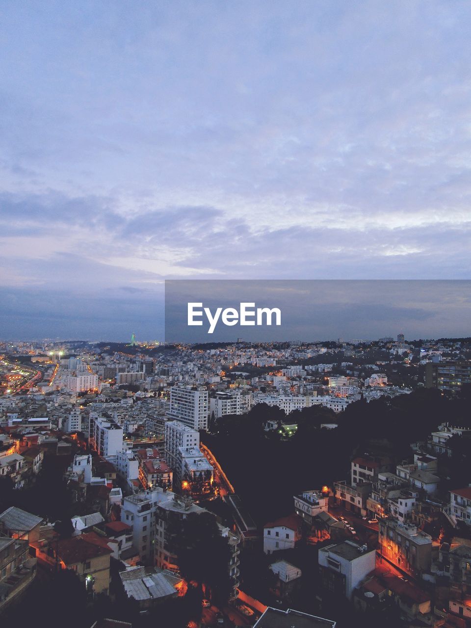 HIGH ANGLE VIEW OF ILLUMINATED CITY AGAINST SKY