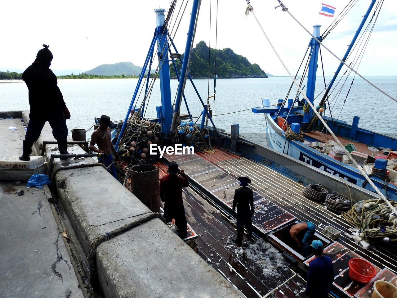 PEOPLE WORKING IN BOAT MOORED ON SEA