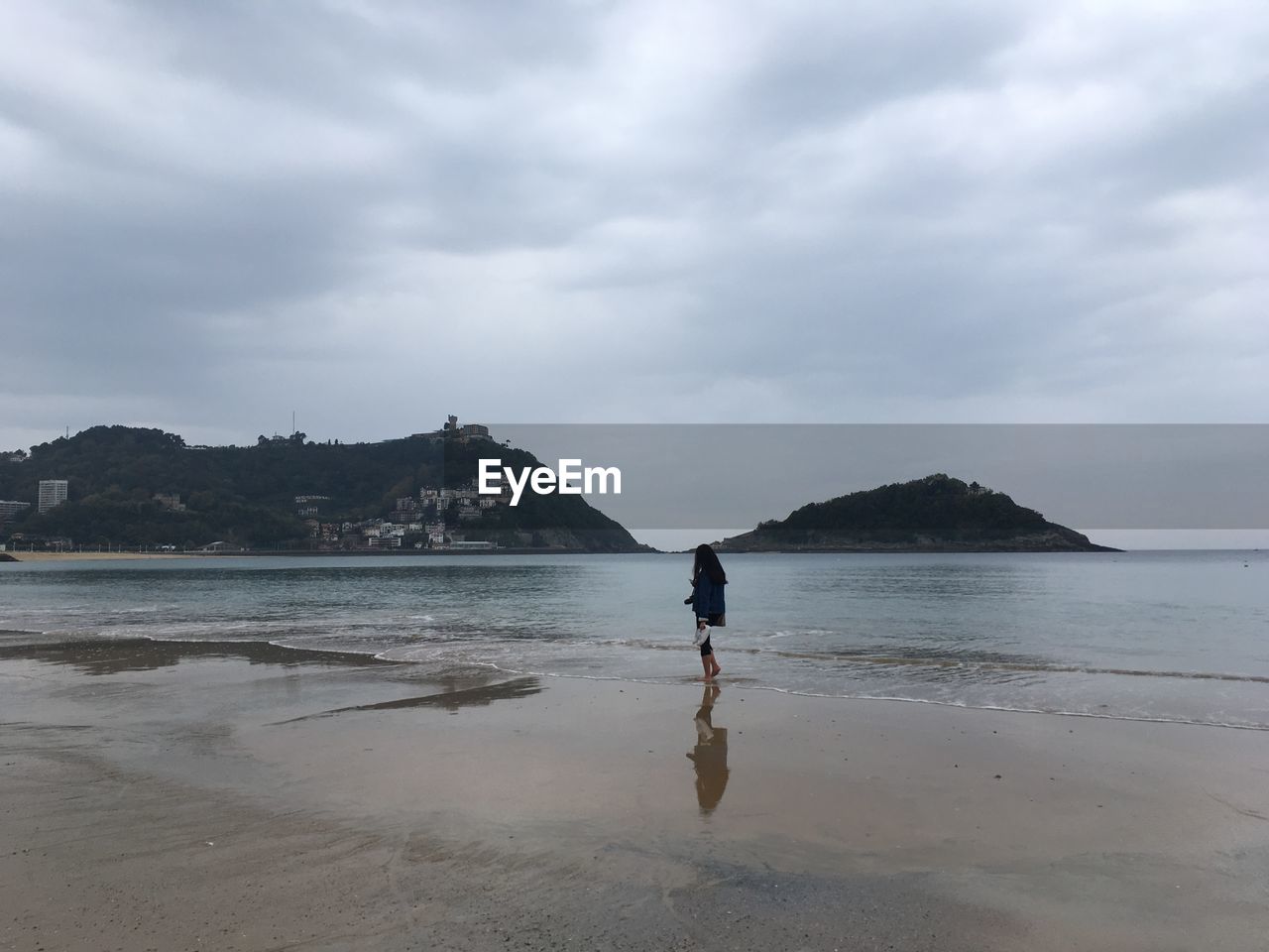 Woman standing at beach against sky