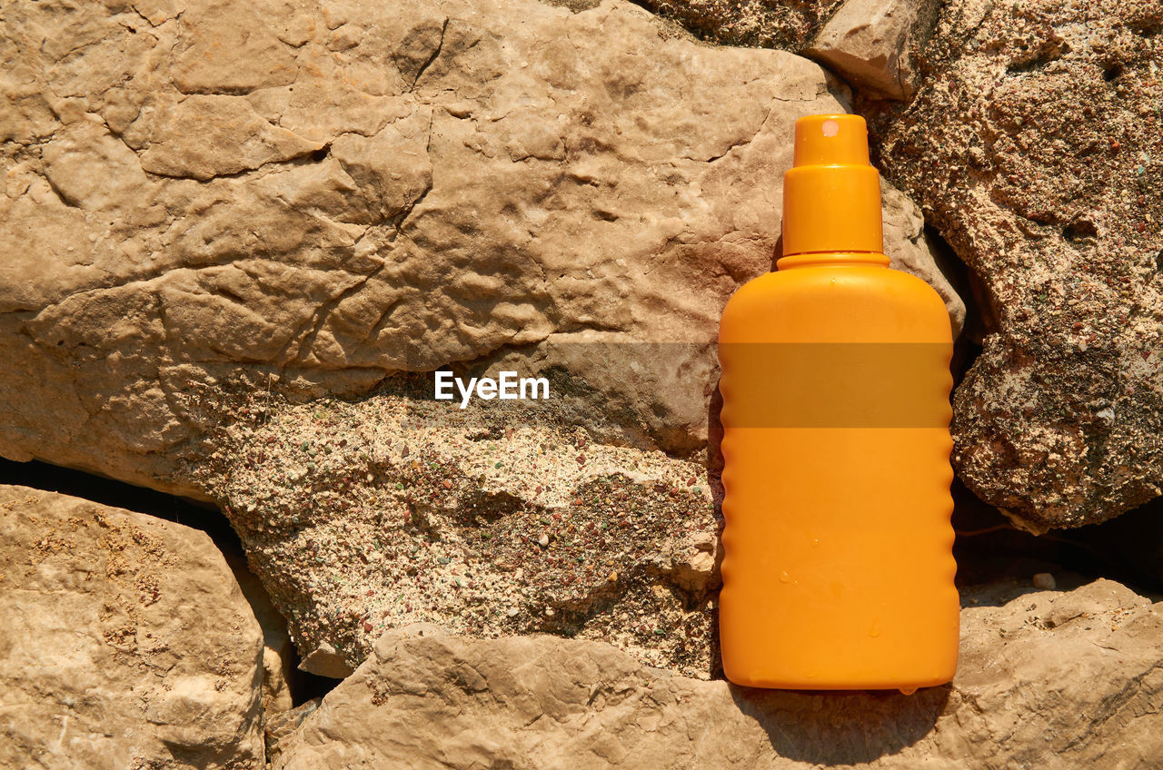 Orange container of a sun protection cream on a stone background