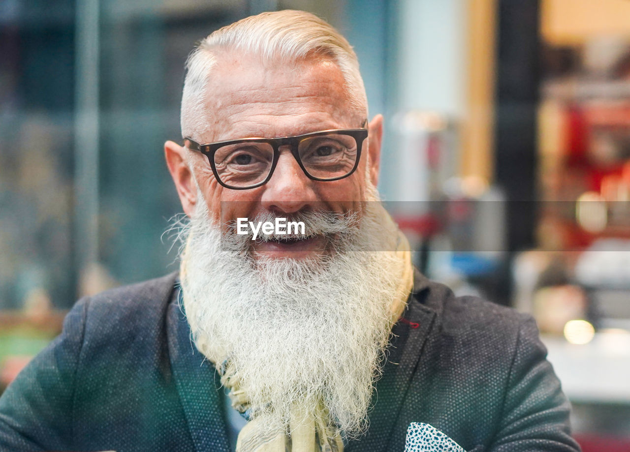 Portrait of bearded man wearing eyeglasses sitting in cafe