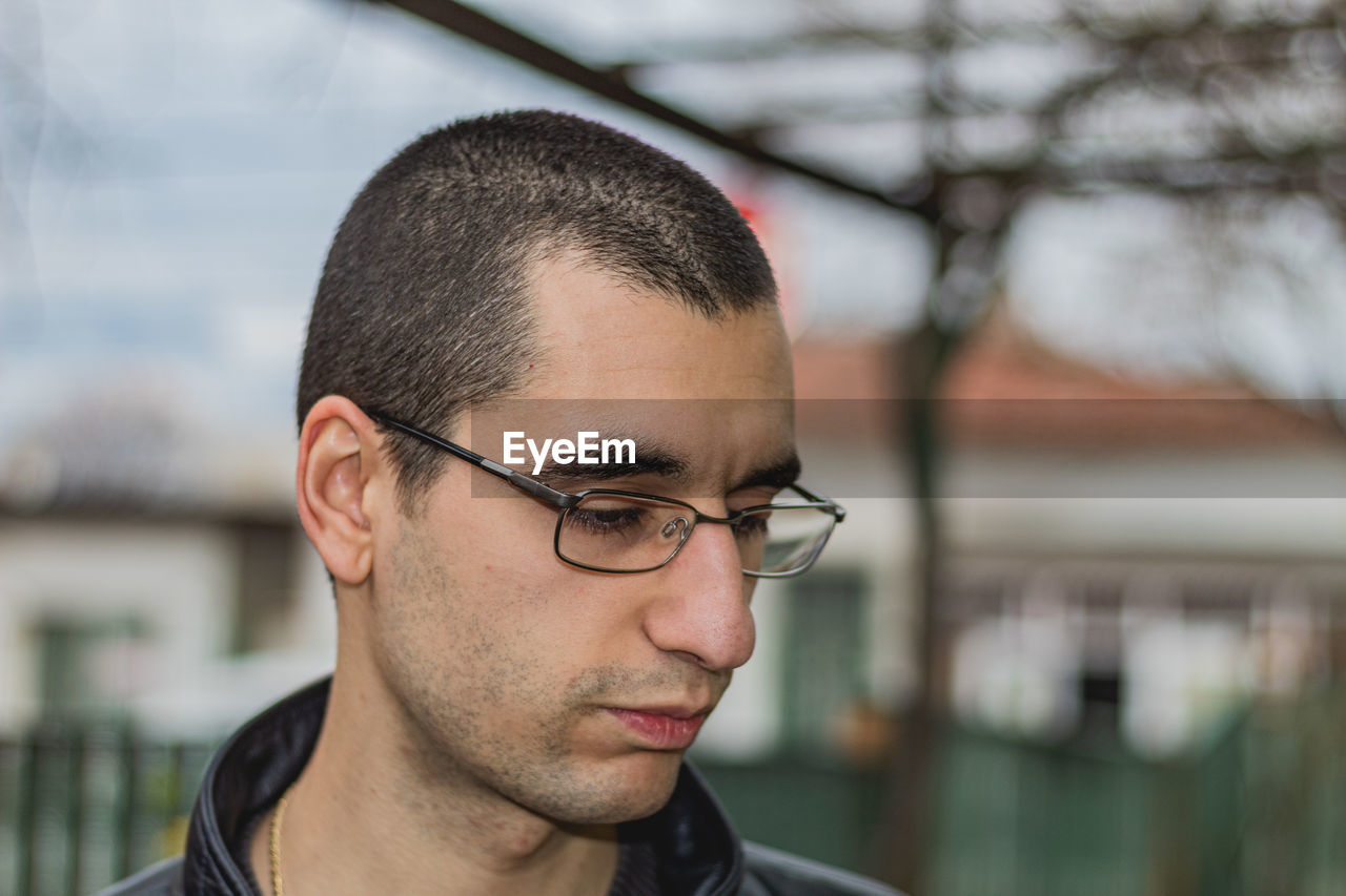 Close-up of thoughtful young man wearing eyeglasses while standing outdoors