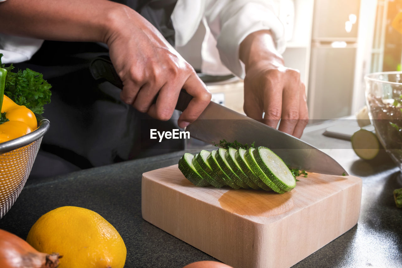 Midsection of man chopping vegetables on cutting board