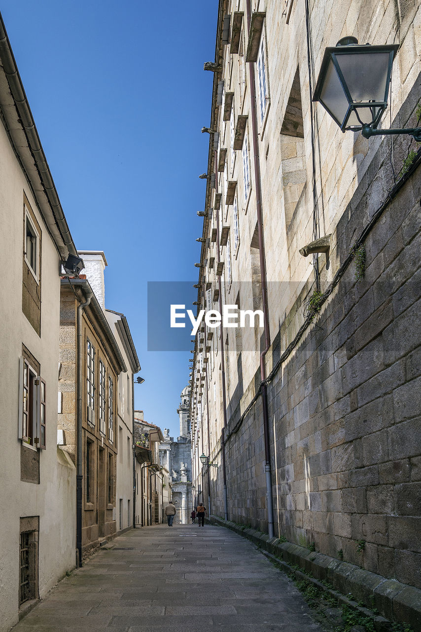 NARROW STREET BETWEEN BUILDINGS AGAINST SKY