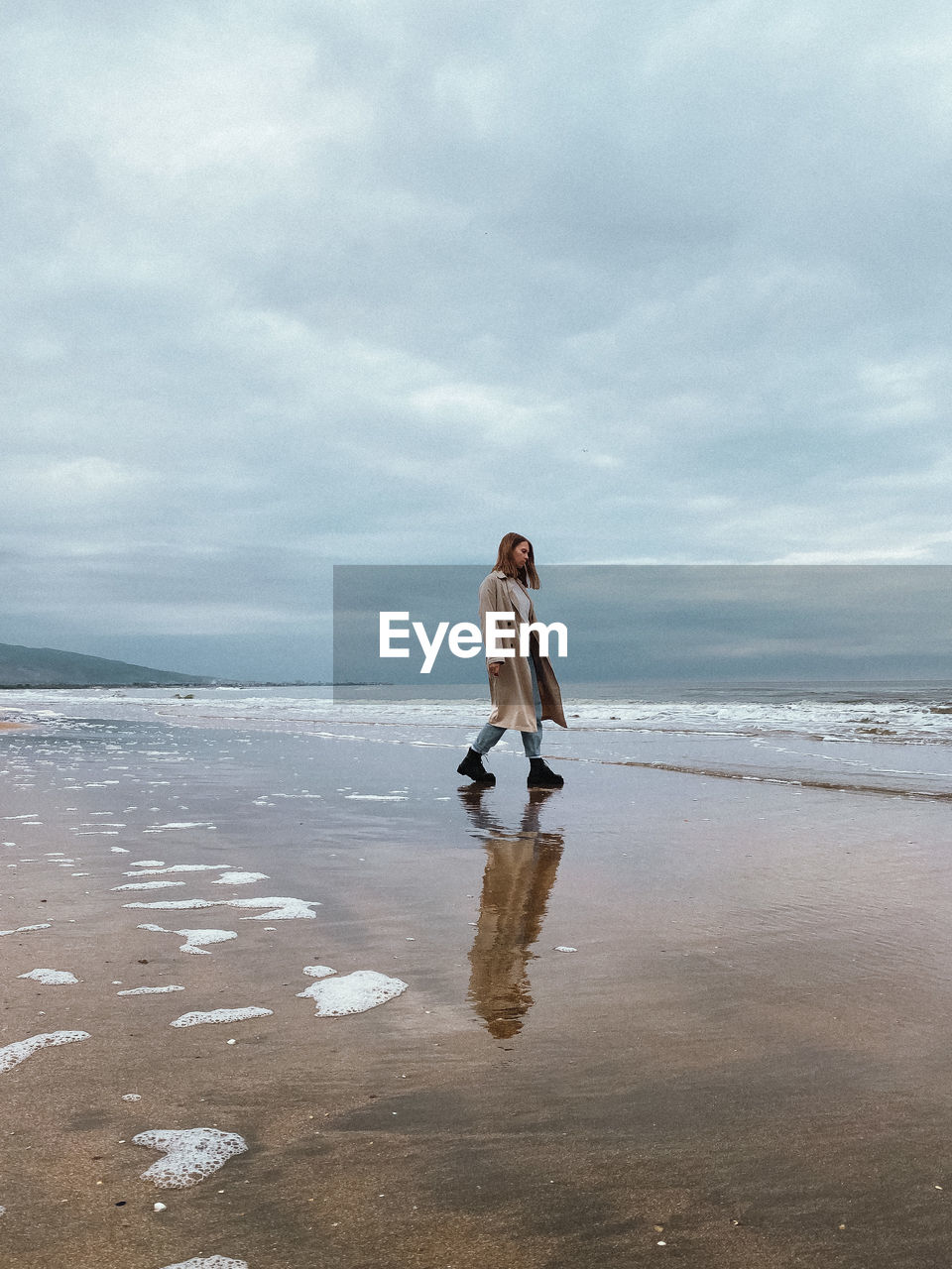 Woman standing at beach against sky and sea