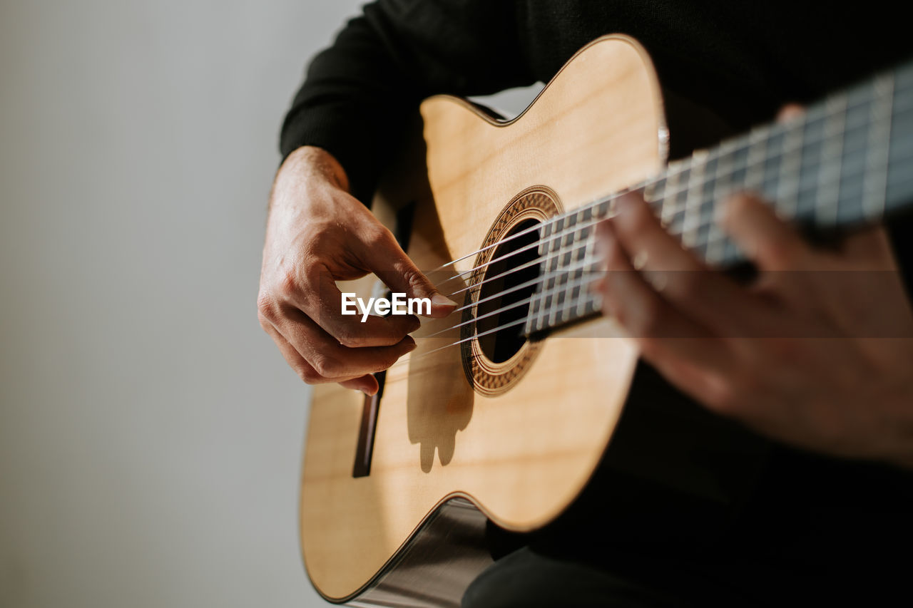 Midsection of man playing classical guitar