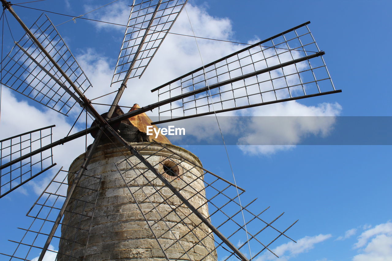 Low angle view of traditional windmill against cloudy blue sky on sunny day