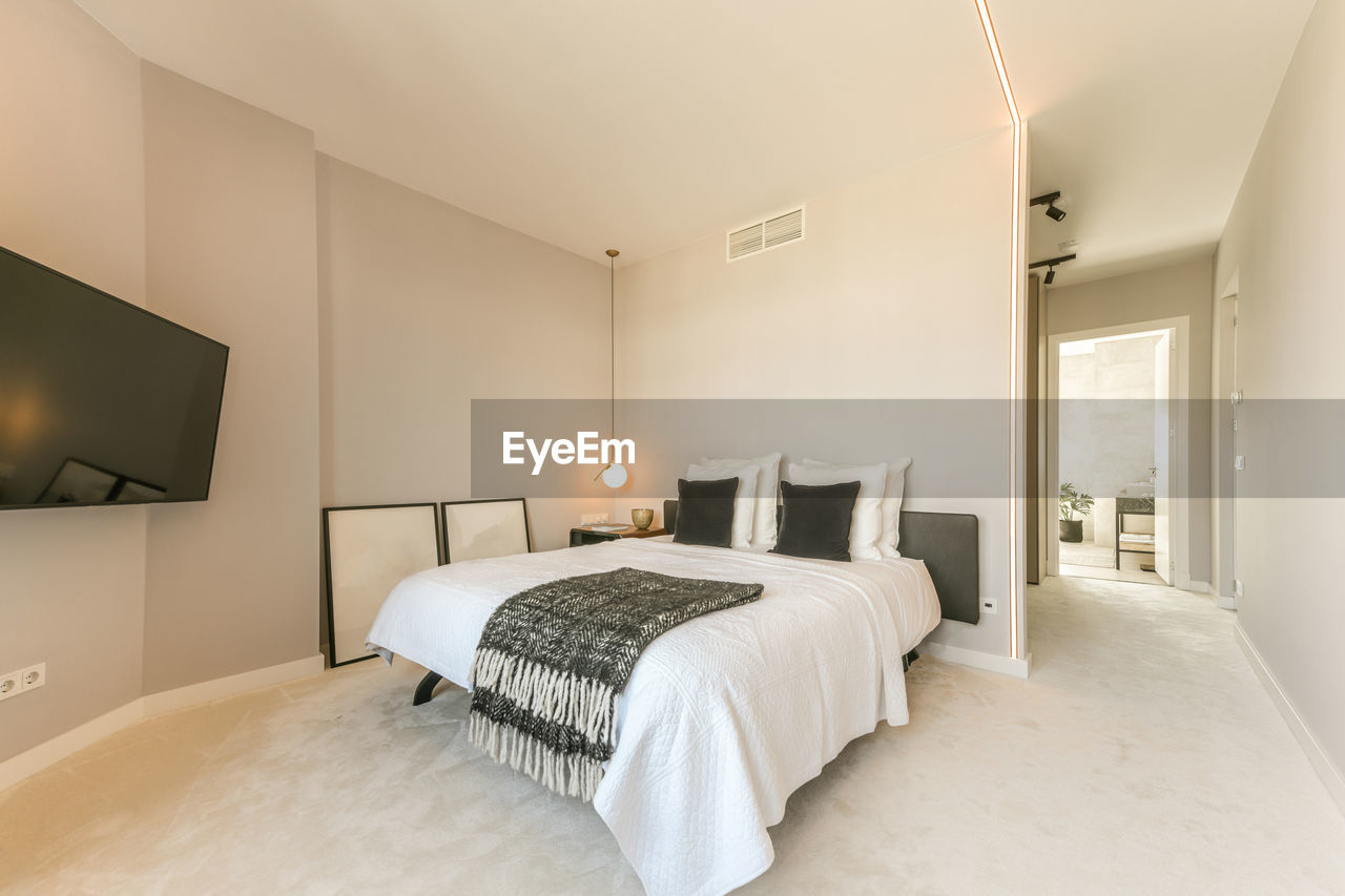 Interior of bedroom with soft bed with pillows and modern tv