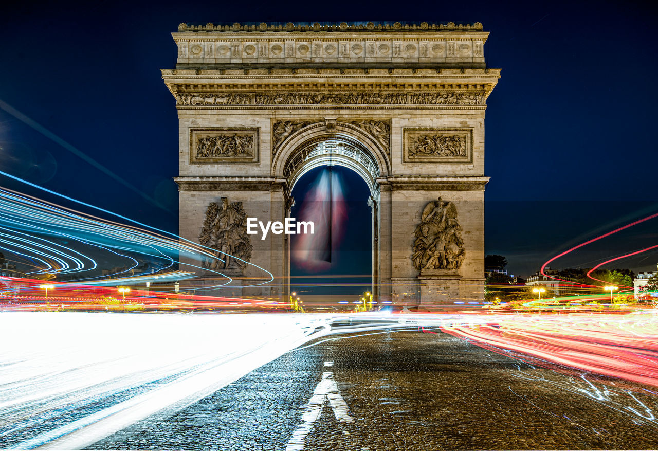 Light trails against arc de triomphe at night