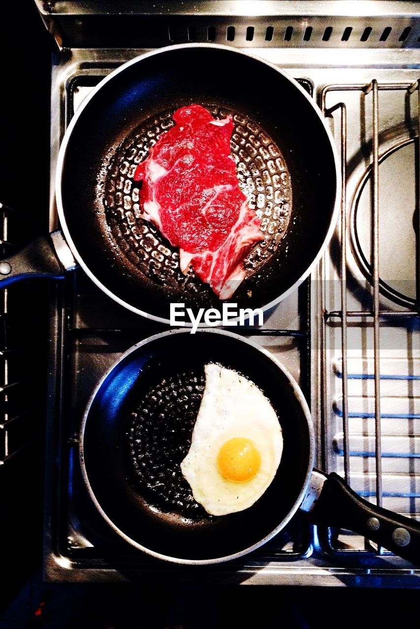 Directly above shot of egg white and steak in cooking pan on stove