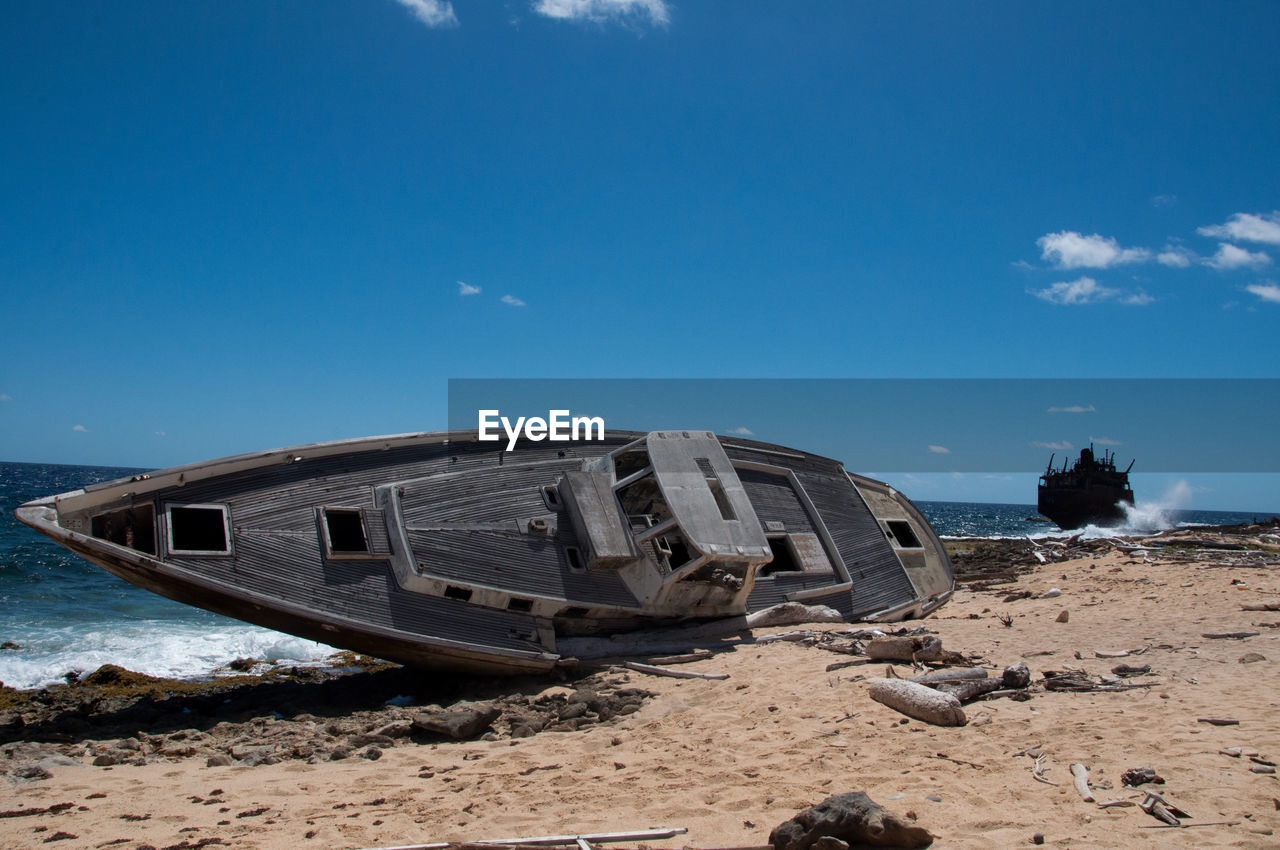 sky, sea, beach, land, vehicle, nature, coast, transportation, water, ocean, sand, abandoned, mode of transportation, nautical vessel, cloud, blue, shore, shipwreck, damaged, no people, scenics - nature, travel, ship, travel destinations, outdoors, ruined, day, coastline, environment