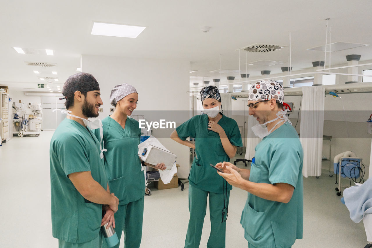 Surgeon using smart phone having discussion with colleagues in hospital