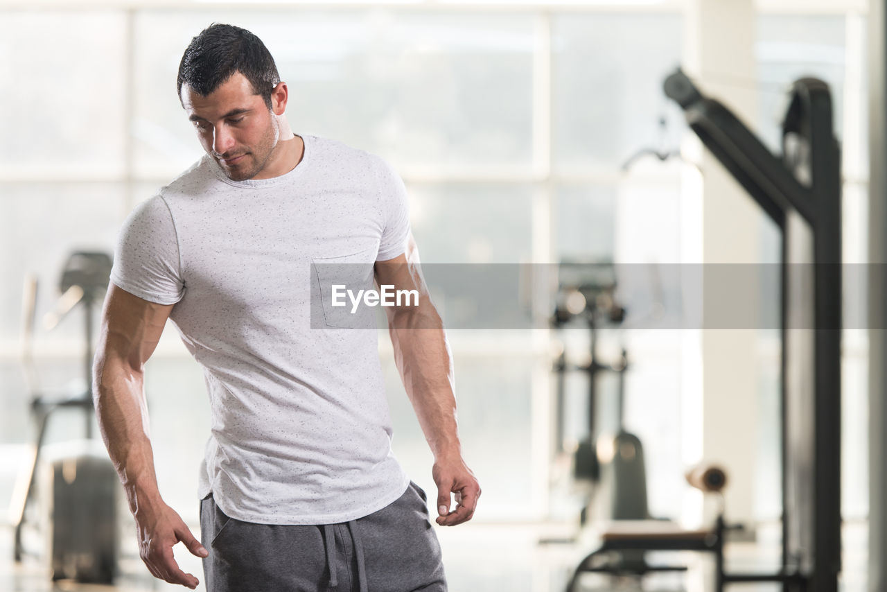 Muscular man looking away while standing in gym