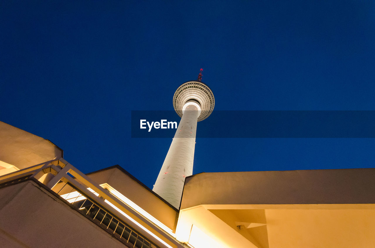 Low angle view of illuminated building and fernsehturm against clear blue sky