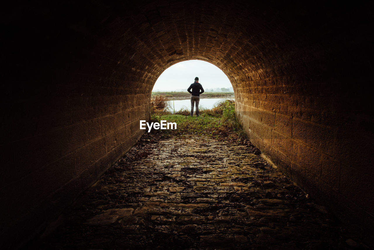 REAR VIEW OF SILHOUETTE MAN IN TUNNEL