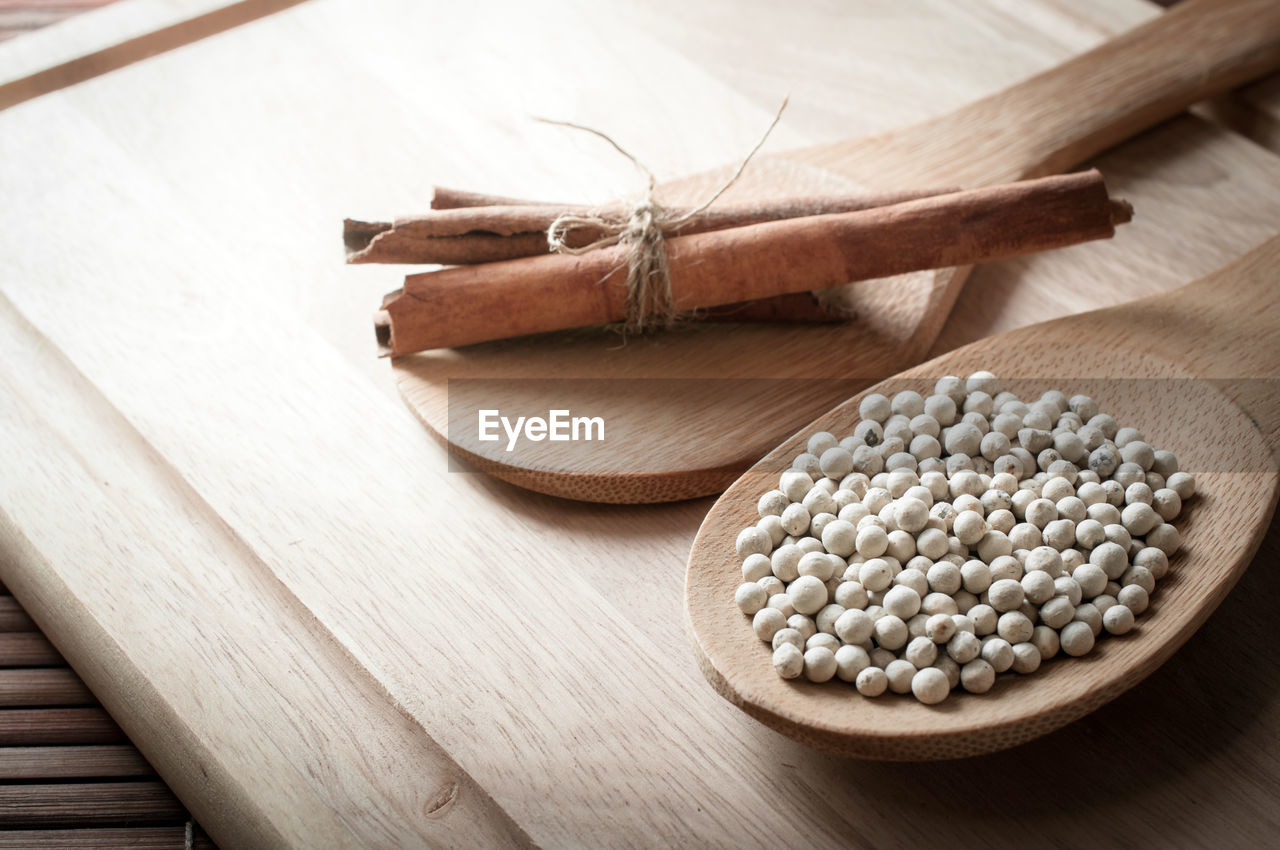 High angle view of white peppercorns with cinnamon and star anise on cutting board