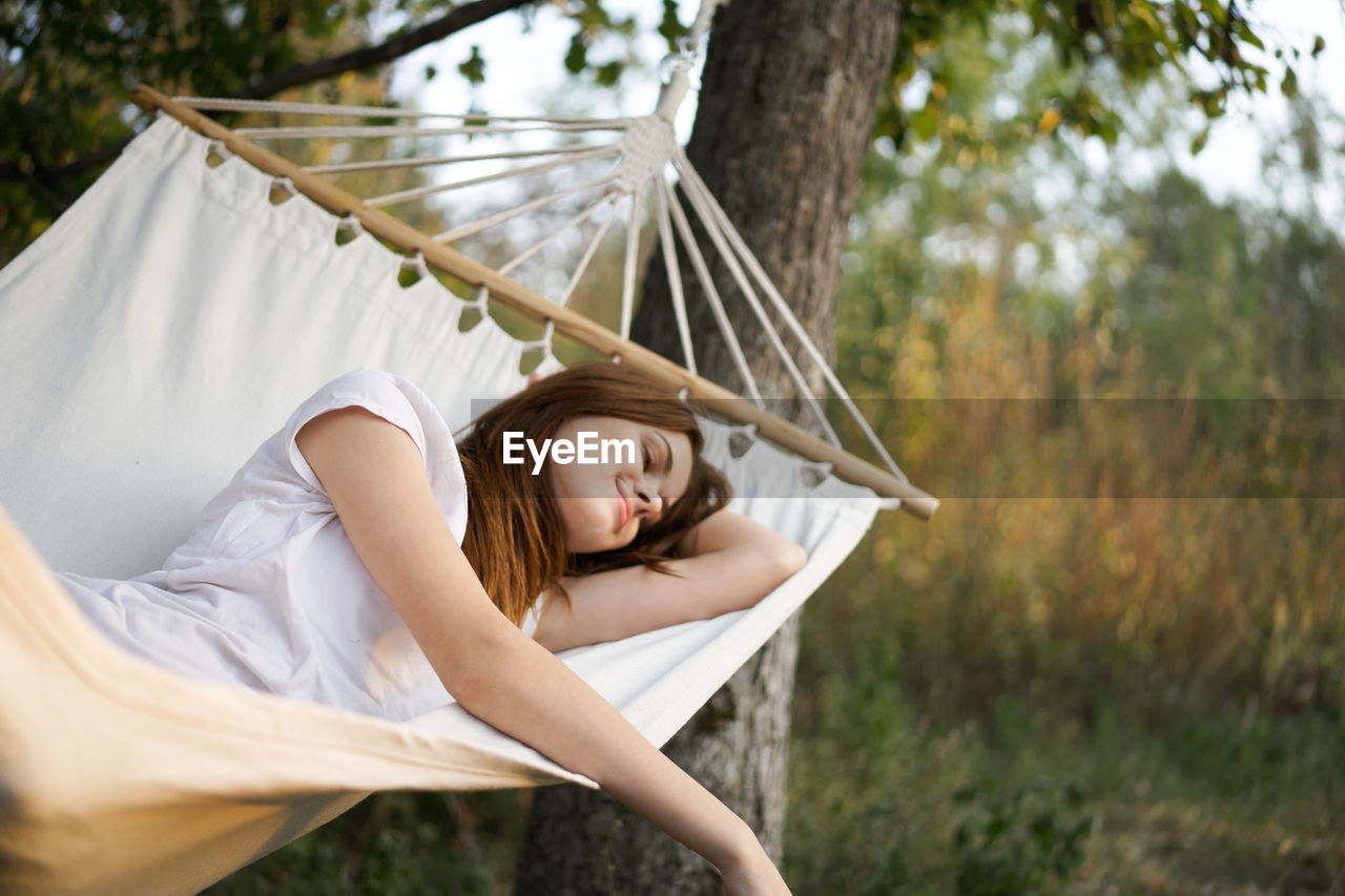 Side view of young woman relaxing on hammock