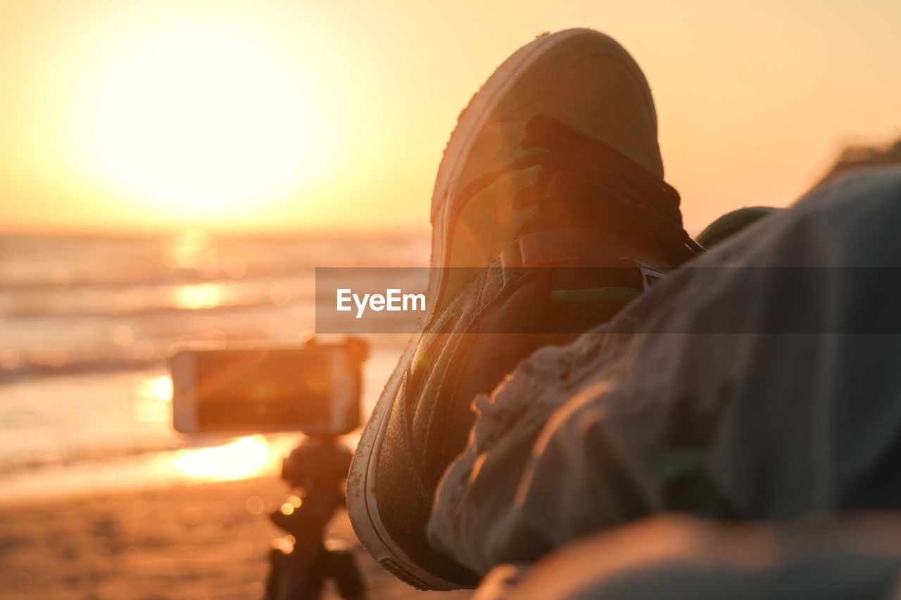 Close-up of shoe by sea during sunset