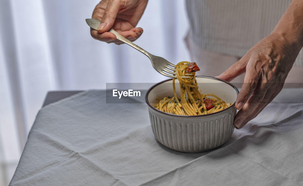 Hand female holding a fork with spaghetti pasta.