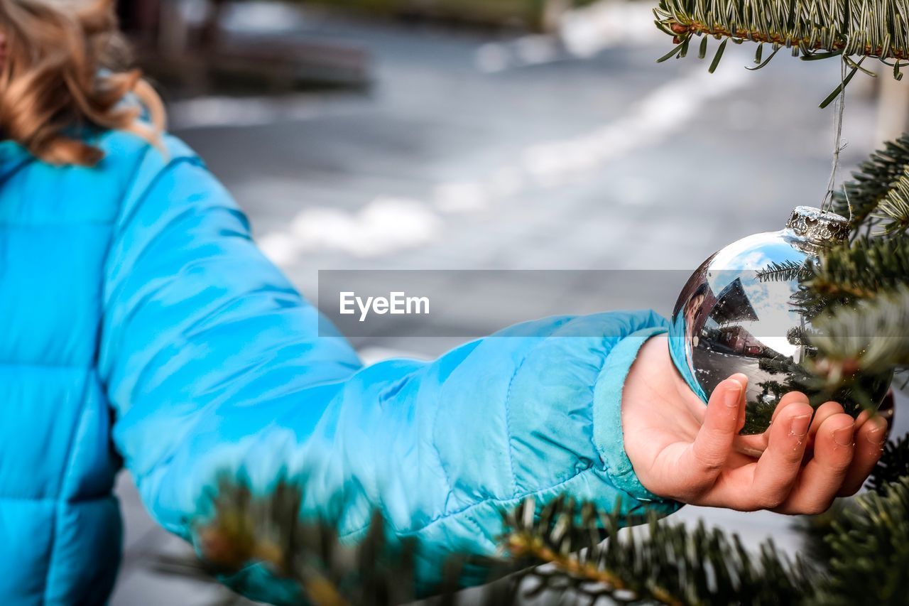 Cropped hand of girl holding christmas decoration