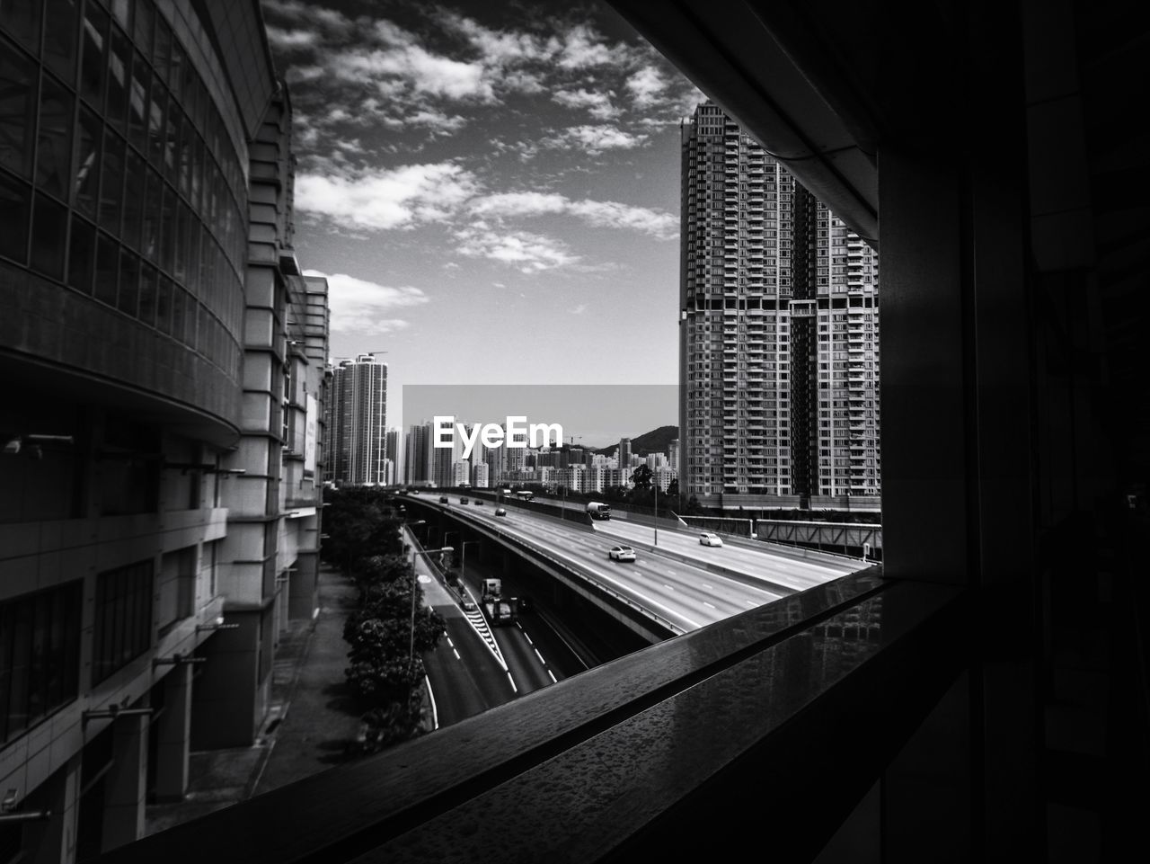 Buildings in city against sky seen through glass window