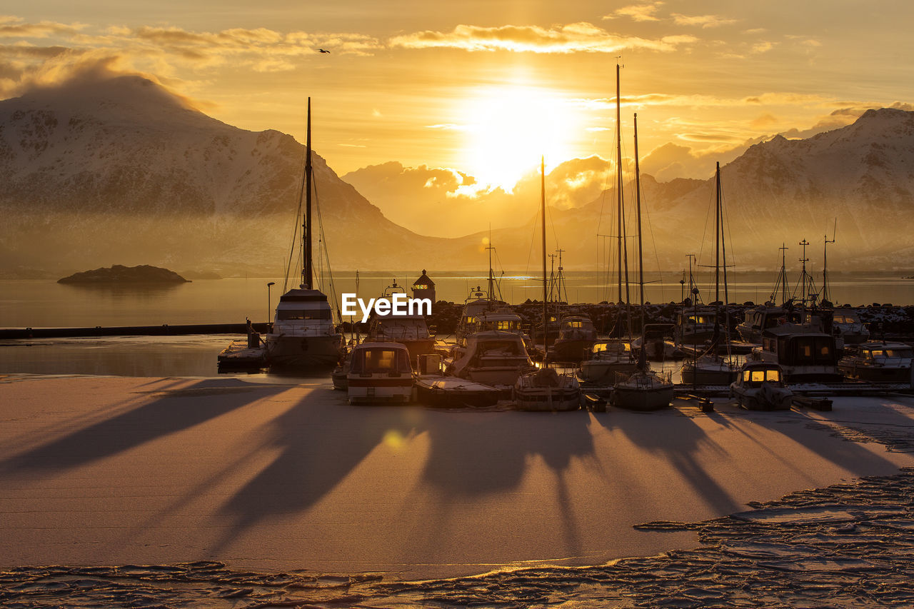 Boats moored at harbor against sky during winter