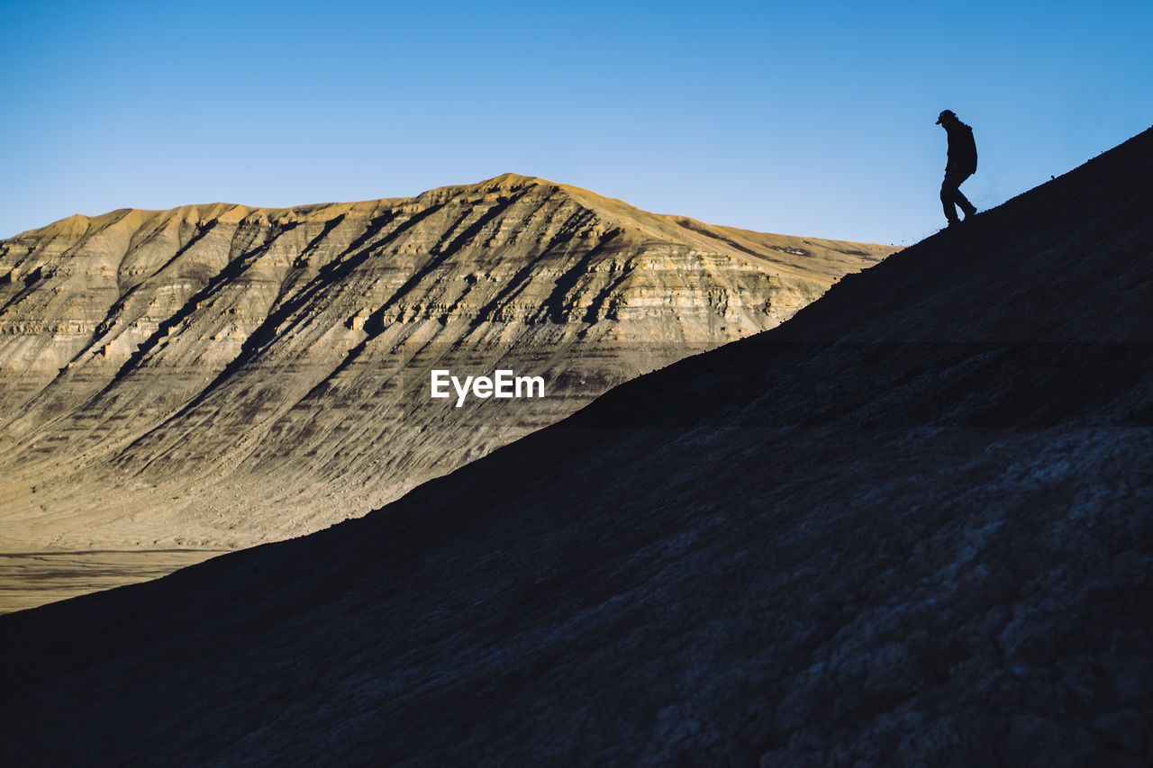 Low angle view of man standing on rock against sky