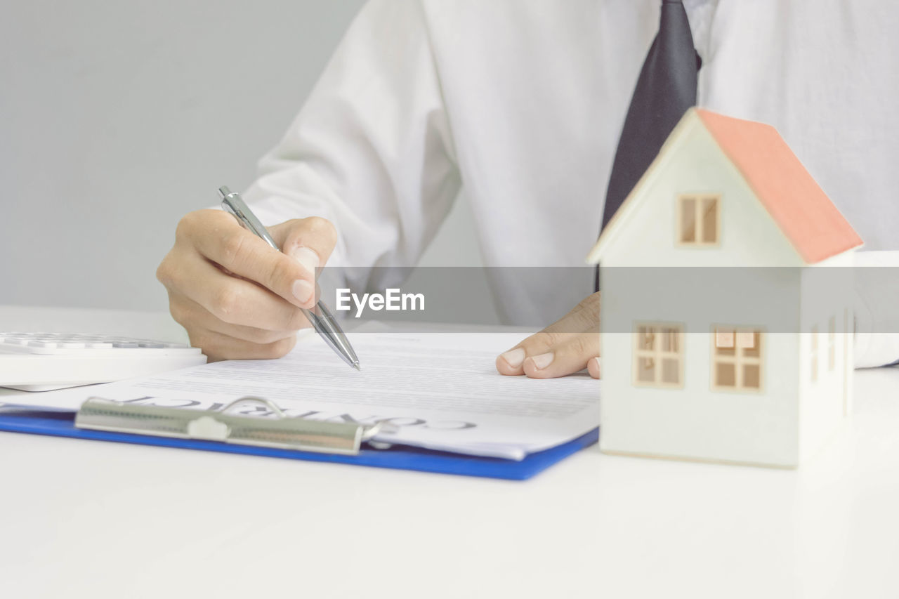 Midsection of real estate agent with contract paper working on table