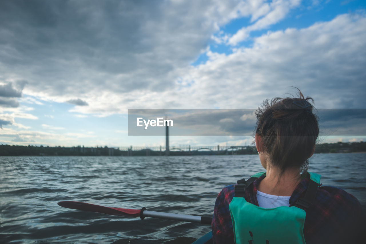 Woman exploring by the river. young woman on kayak in the sea with blue sky