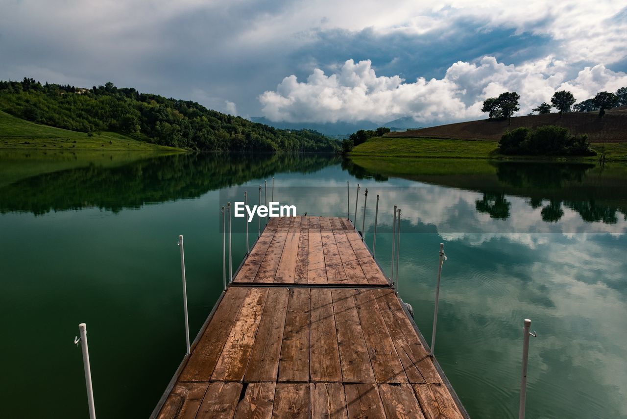 Empty wooden pier over lake against sky