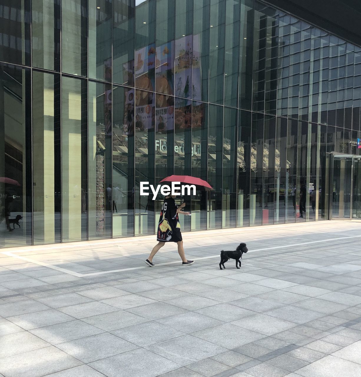 WOMAN WALKING ON FOOTPATH IN CITY